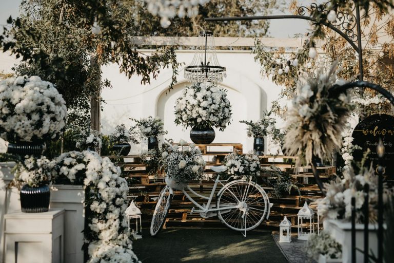 Charming outdoor wedding setup adorned with white flowers and a classic bike, creating an elegant ambiance.